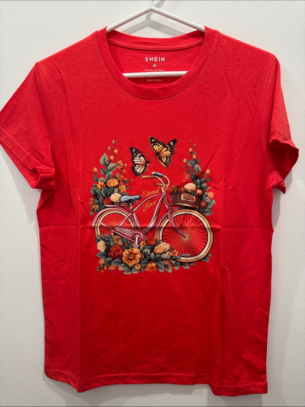 woman graphic t-shirt  featuring a floral bicycle design with butterflies